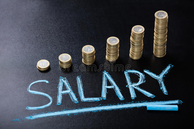 salary-concept-stacked-coin-blackboard-high-angle-view-89193698